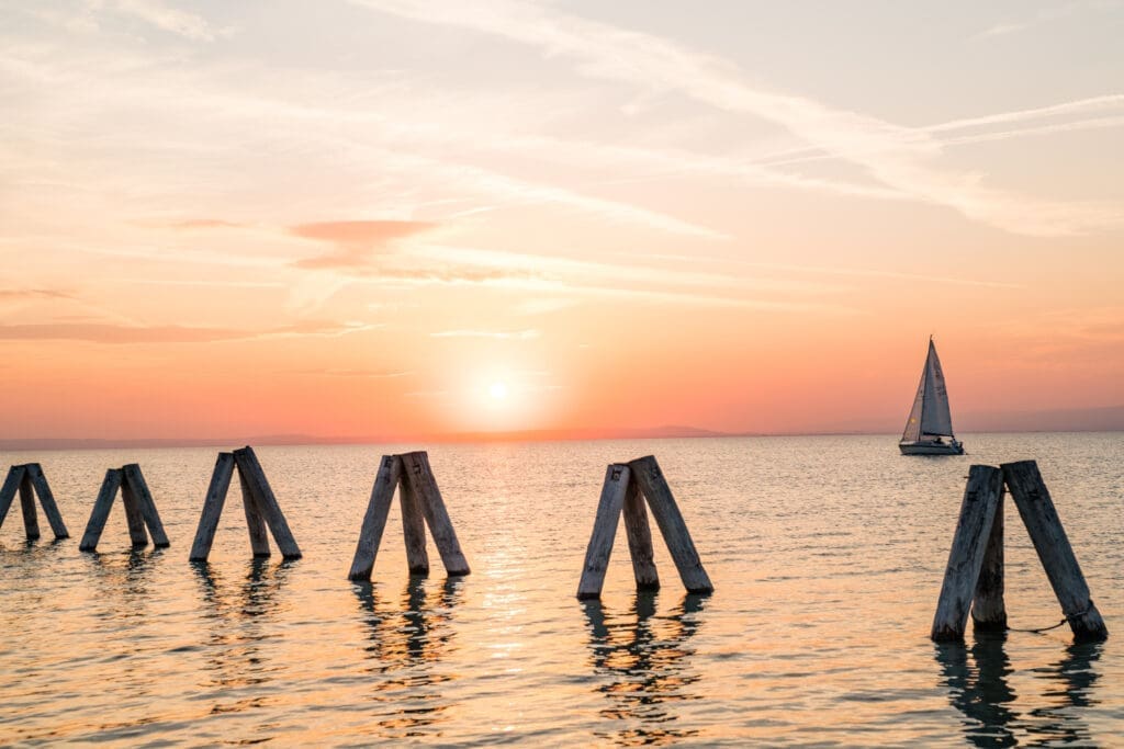 Naplemente a Fertő tónál, a háttérben vitorlás hajóval